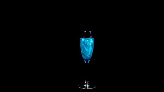 Glass with blue liquid. The elixir spins and overflows with liquid. Potion of love is isolated on a black background.