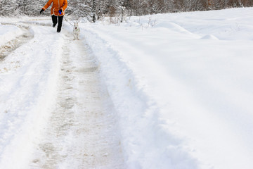 Young woman making a morning run with a husky puppy in the winter forest.