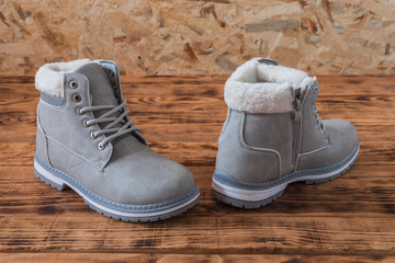 Leather boots with fur inlay on wood background, close-up