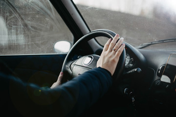 female hand holds the steering wheel of a car. Woman driver concept.