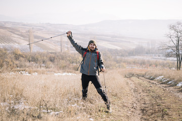 Male hiker waving with pole on mountain