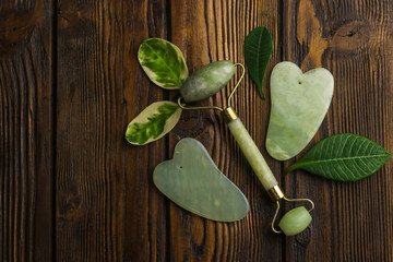 Facial and body stone massage instruments on light wooden background
