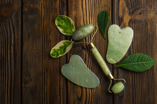 Facial and body stone massage instruments on light wooden background