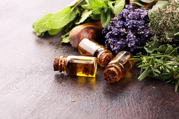 Fresh herbs from the garden and the different types of oils for massage and aromatherapy on table with lavender