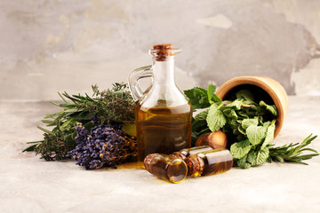Fresh herbs from the garden and the different types of oils for massage and aromatherapy on table with lavender