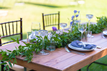 Beautifully decorated wooden table in a summer open-air cafe. Green branch and fresh flowers table...