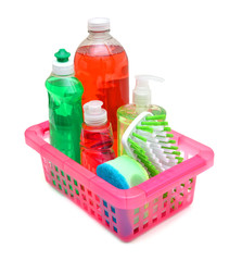 Plastic bottles of cleaning products, sponges and brush in basket on white background
