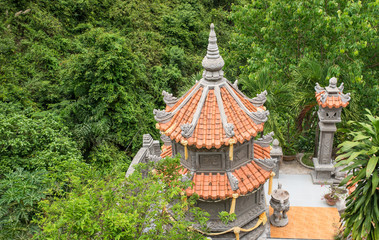 A small Buddhist pagoda that is hidden in the greenery of tall trees and dense bushes. Vietnam.