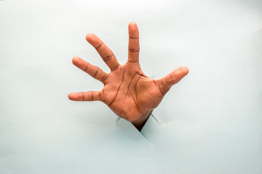 Black Person Hand Through A Hole In A Cardboard With Open Palm Spread Out Showing All Five Fingers