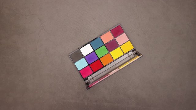 Colorful woman eye shadow palette spin in circle on grey background - Looping stop motion 