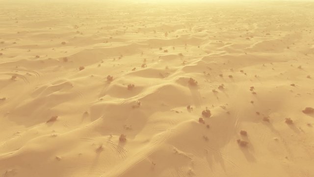 Aerial shot of desert sand dunes with car tracks, UAE