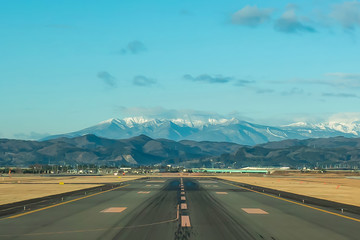 Beautiful view of Sendai Airport, Miyagi in Japan on runway in daytime with clear sky, behind is big mountain Zao covered with snow on top. Aviation airport environment background, wallpaper concept.