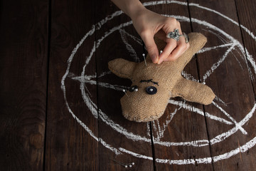 Voodoo doll on a wooden background with dramatic lighting. The concept of witchcraft and black art...