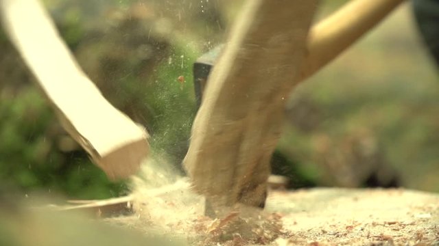 Slow motion close up shot of a axt / hatchet cutting / smashing a log of wood / billet of wood