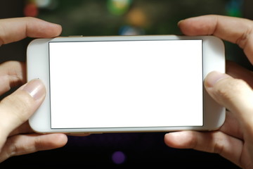 Hands of young gamer boy playing video games on smartphone and computer in dark room wearing headphones and using backlit colorful keyboard