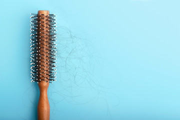 Wooden comb with fallen hair on a blue background, concert of hair loss.