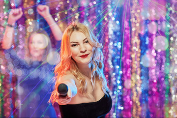 Portrait of happy pretty blonde having fun and singing at karaoke club