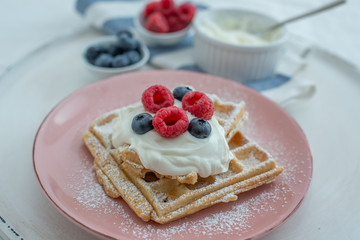 Fresh sugar waffles with castor sugar and berries