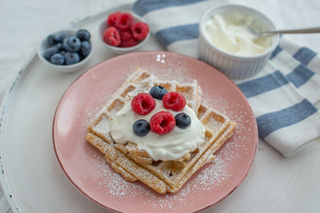 Fresh sugar waffles with castor sugar and berries