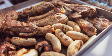 Grilled sausages and chicken legs on charcoal grill