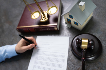 Judge With House Model Writing On Paper