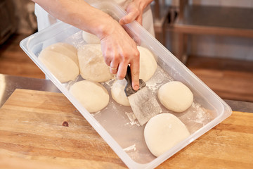 Dough for Neapolitan pizza. Closeup hand of chef baker in uniform white apron cook pizza at kitchen
