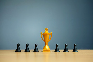 Golden trophy in the middle of chess pawn