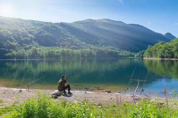 Fishing adventures, carp fishing. Man fishing on lake. Concept of patience, waiting, relaxation and healthy lifestyle in the nature 