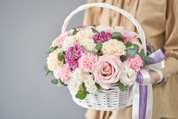 Flowers delivery. Flower arrangement in Wicker basket. Beautiful bouquet of mixed flowers in woman hand. Floral shop concept . Handsome fresh bouquet.