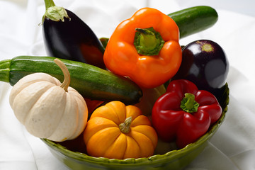 Bowl full of vegetables including peppers pumpkins eggplants and zuchinis