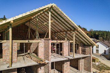 Wooden frame of new roof on a brick big house under construction.
