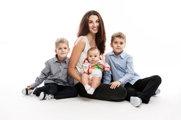 Young smiling mother with three children are sitting on a white background. A happy family.