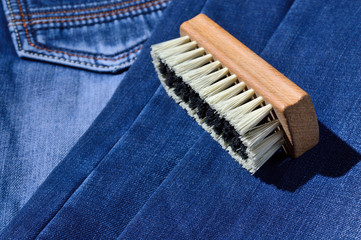 a clothes brush lies on folded jeans.