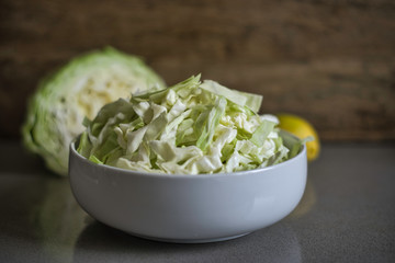 Chopped cabbage in ceramic bowl over gray marble background. Raw food diet.