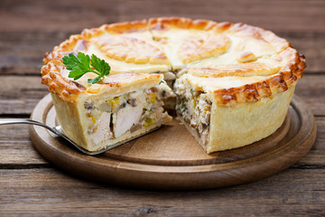 Traditional homemade chicken meat and mushroom pie on wooden  background.