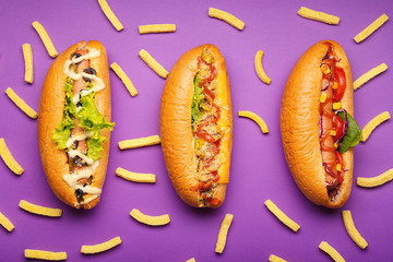 Tasty hot dogs and french fries on color background