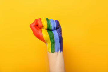 Female hand with painted rainbow on color background. LGBT concept