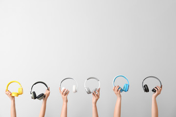 Hands with modern headphones on light background