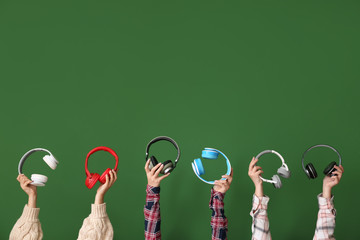 Hands with modern headphones on color background