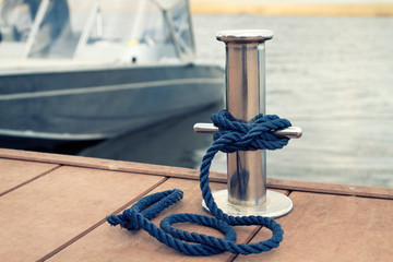 blue mooring rope on a metal bollard on a boat background