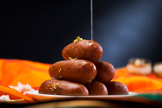 Langchas kept in a plate on an orange cloth with a syrup dripping on top. 	
