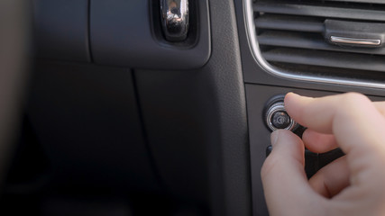 human is adjusting volume of radio inside car, rotating handle on control panel, close-up of hand