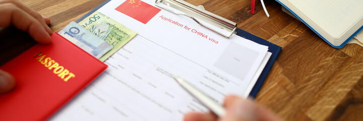 Male hand hold silver pen with passport. Filling China apllication form concept