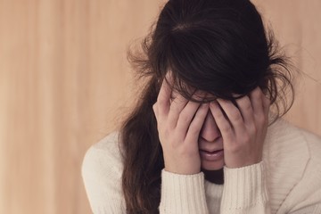 Emotional portrait of sad young woman holding her head in hands