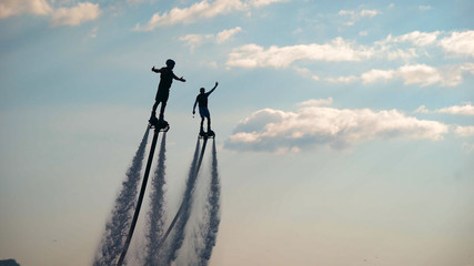 Flyboarding. Two athletes fly on flyboards above the water. Men perform various tricks and turns....