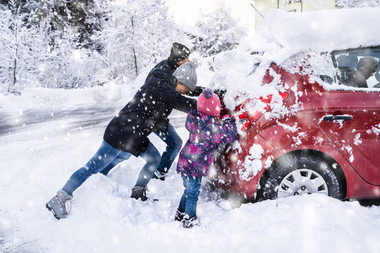 Family Pushing A Car Stuck In The Snow