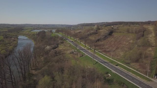 Cars move along a highway located among green hills. Transport connection. Voltage traffic on the road. Aerial photography from a drone or quadrocopter. Picturesque area for traveling by motorcycle
