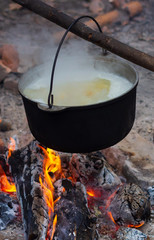 Campfire outdoors at inhabited place. Cooking meal with open fire and old coocking equipment. Cooking process when travel far from home.