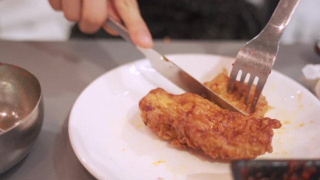 4k Asian female hand using knife and forks cutting piece of fried chicken, lunch together, food advertisement, commercial meal, Korean fried chicken restaurant, hot sauce, dinner table manner, indoors