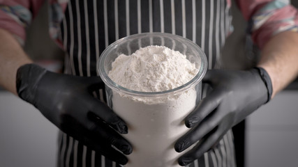 Flour, the main ingredient for the dough. unknown chef man, holding a large jar of flour. Cooking